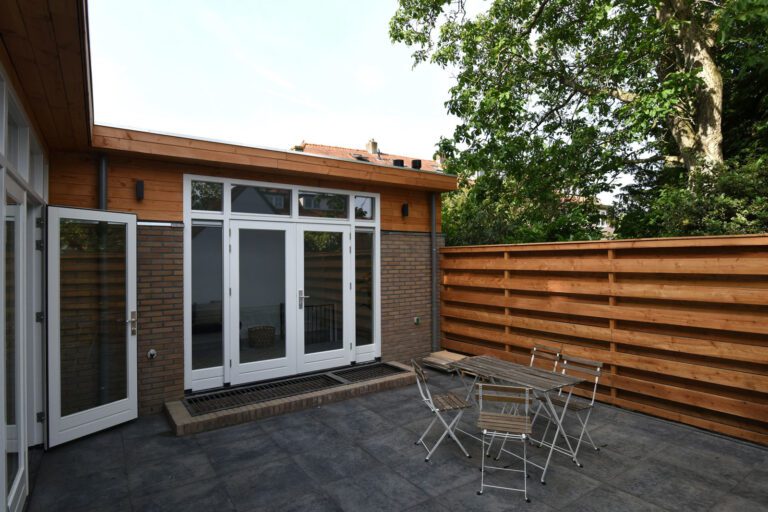 Terras naast de uitbouw met openslaande deuren en houten boeiboord – Eikbosserweg 210, Hilversum