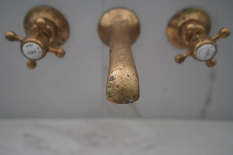 Brass wall-mounted taps on a marble wall