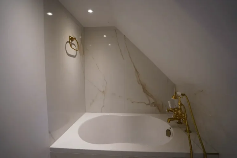 Marble bathtub under a sloped ceiling with gold fittings