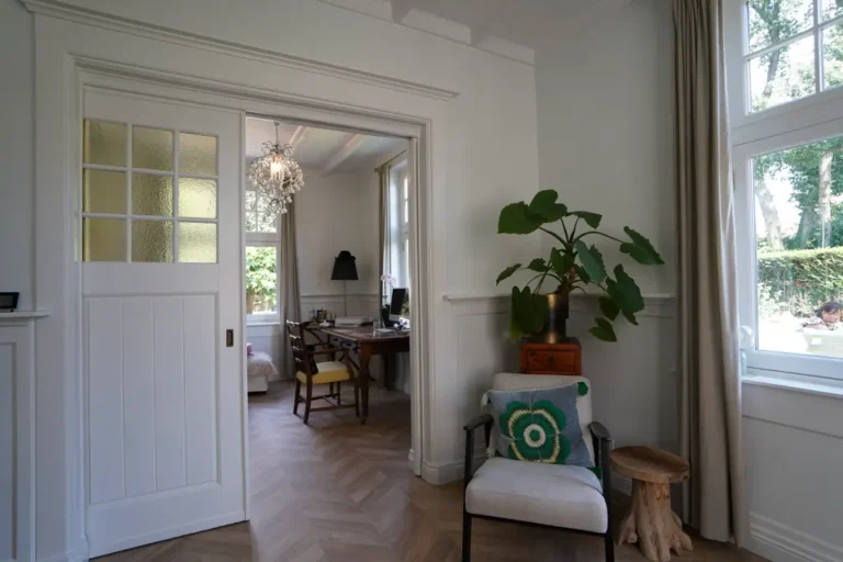 View through white sliding doors into a study with a desk