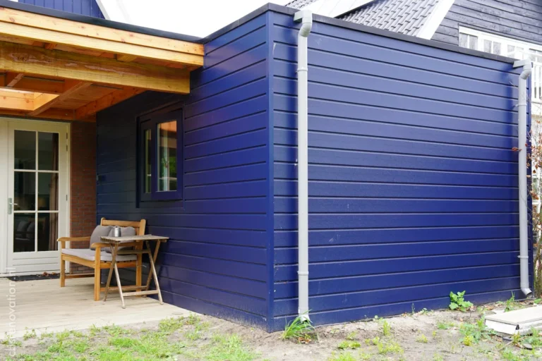 Corner of the dark-blue wood-clad garden extension with a small window