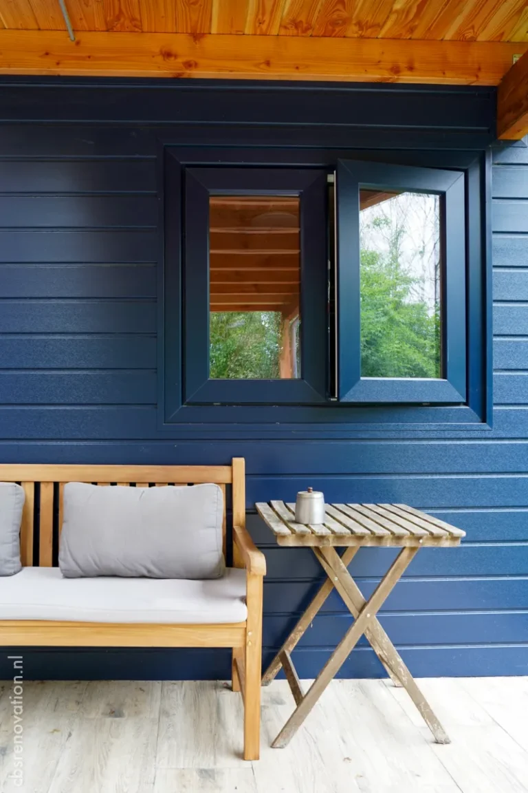 Open black-framed window in the navy garden room wall with a terrace bench