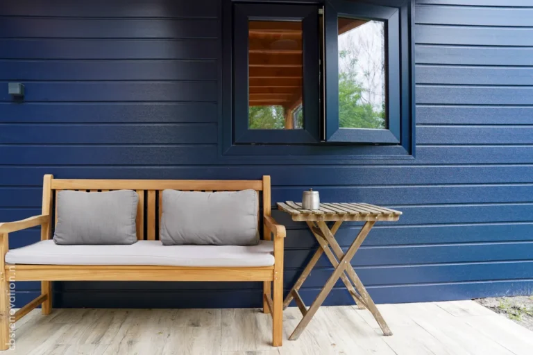 Side of the navy wood-clad garden room with a terrace bench