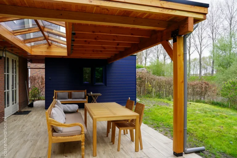 Covered terrace with a lounge sofa and dining table beside the navy garden room