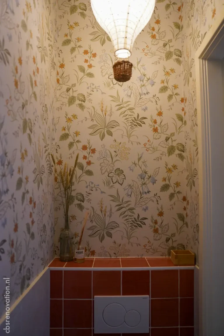 Toilet with botanical wallpaper, terracotta tiles and a pendant lamp