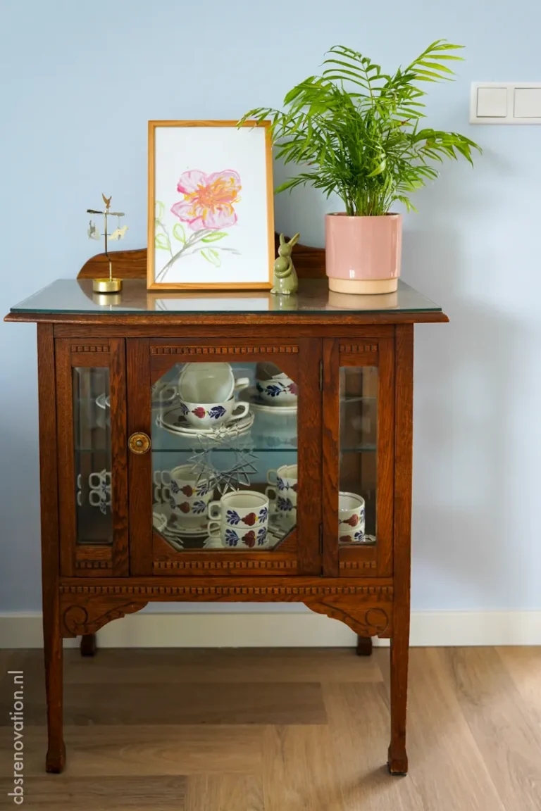 Antique oak display cabinet with china on a blue-painted wall