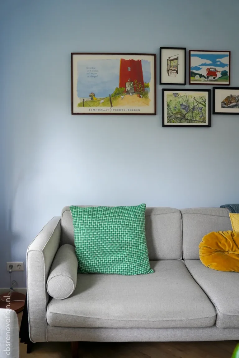 Grey sofa with framed artwork on a blue living-room wall