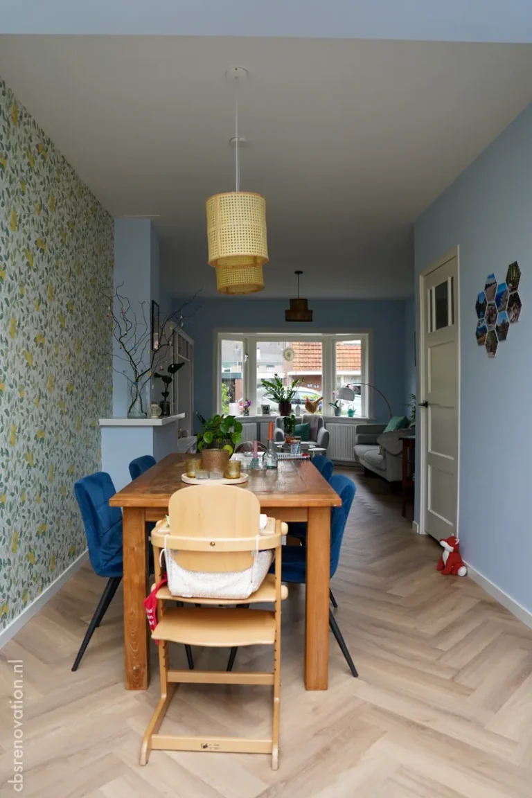 Dining area with a wooden table, blue chairs and a lemon-print accent wall