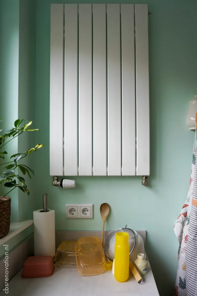 Vertical radiator on a green kitchen wall