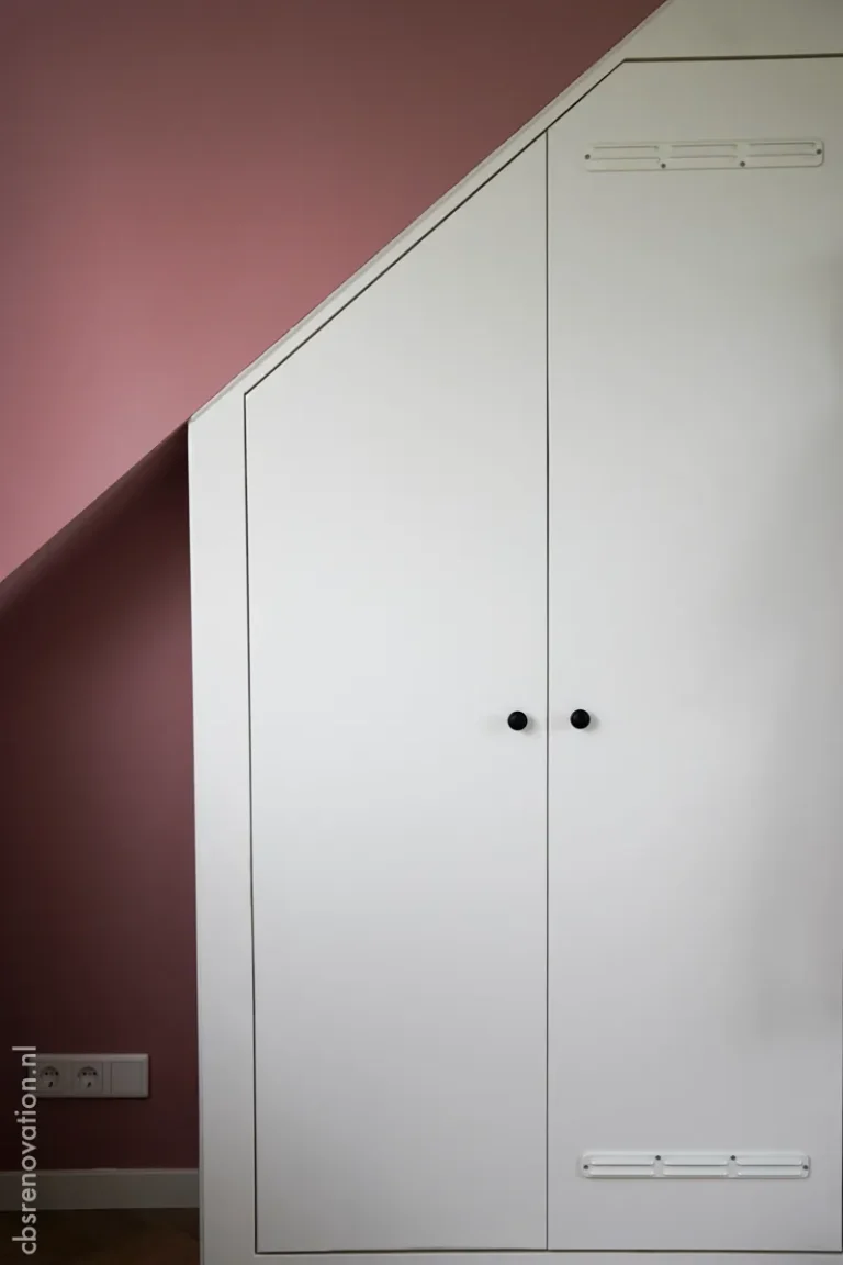 Built-in white wardrobe under a sloped attic ceiling
