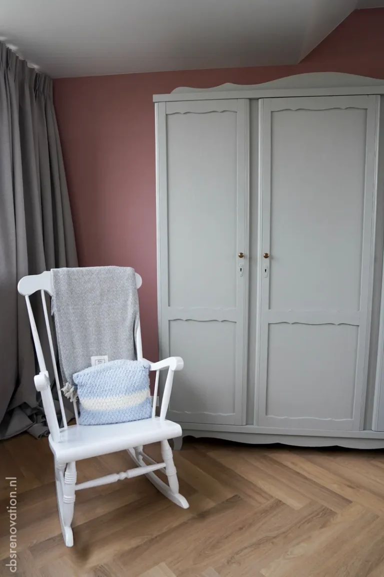 White rocking chair and grey wardrobe on a herringbone parquet floor