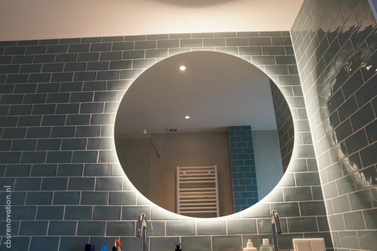 Bathroom with a round backlit mirror on a blue-tiled wall