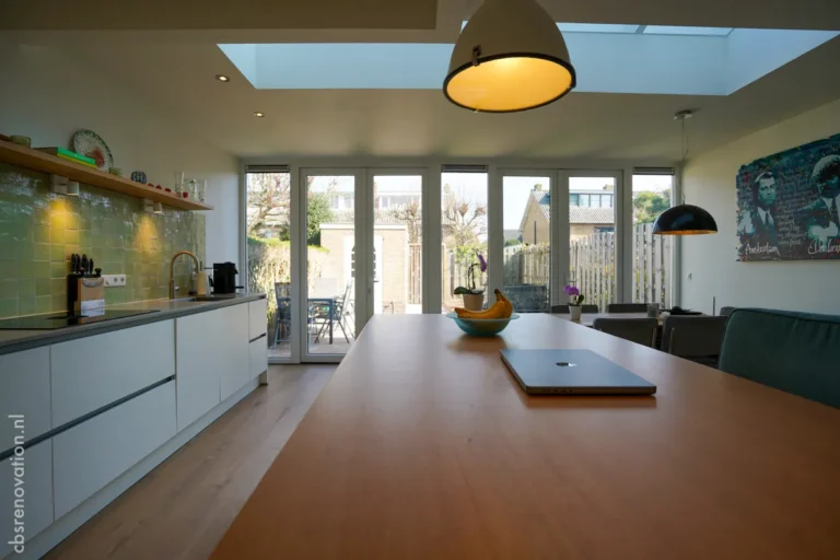 Bright kitchen featuring modern cabinetry, large windows, a skylight, and a wooden island, highlighting a successful renovation project.