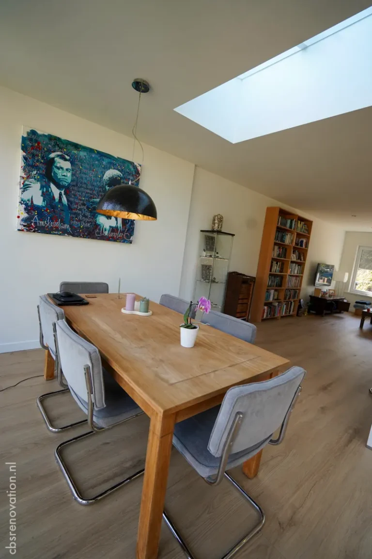 Bright dining area featuring a wooden table, modern chairs, a skylight above, and a colorful wall art for a renovated home.