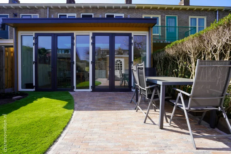 Modern renovations with a glass extension and new patio, featuring a landscaped garden and outdoor seating area.