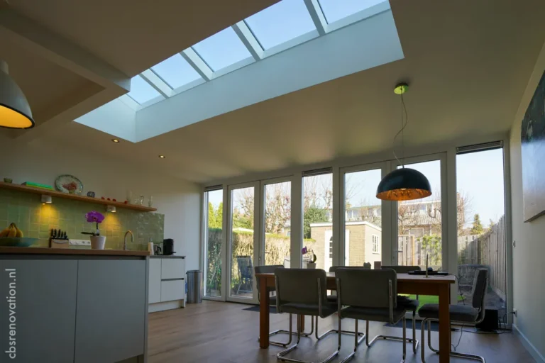 Bright renovated kitchen with skylights, modern furnishings, and a dining table overlooking the garden.