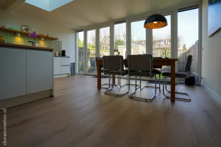 Renovated kitchen and dining area featuring modern furniture, large windows for natural light, and wooden flooring.