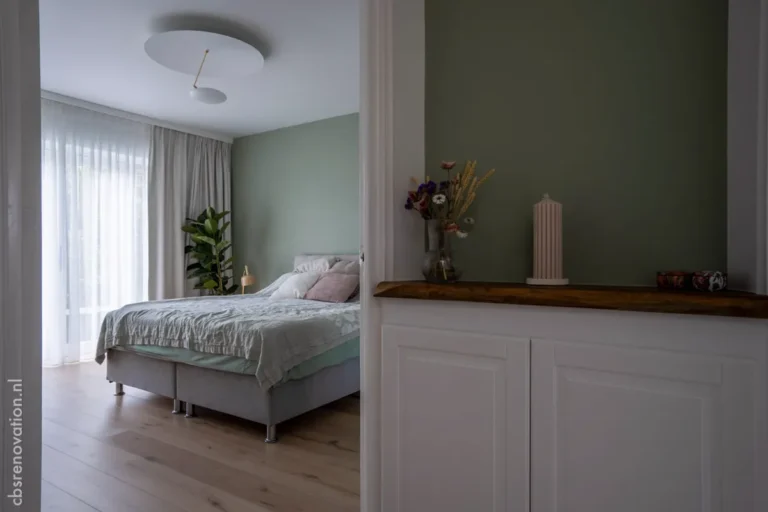 Bedroom with a green accent wall and a storage cabinet