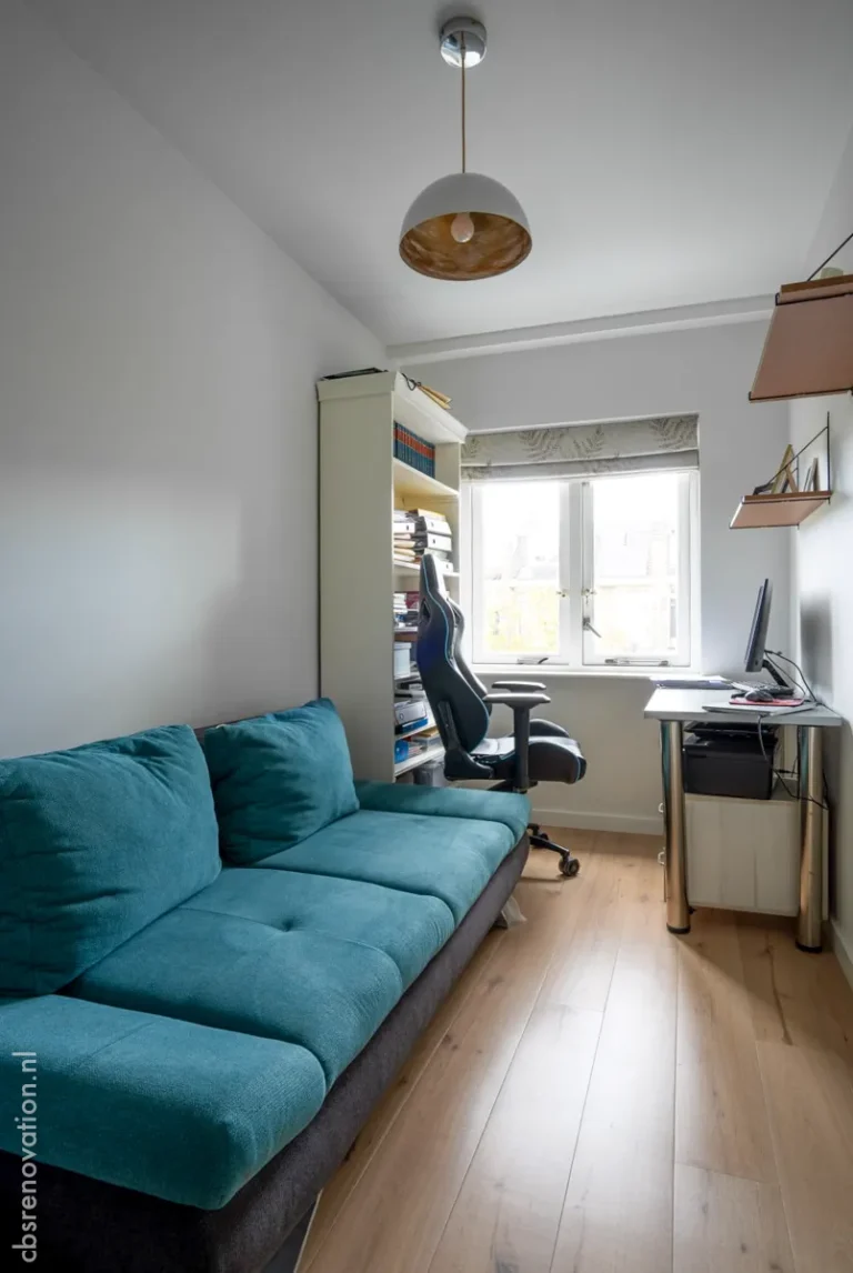 Home office with a teal sofa and a desk by the window