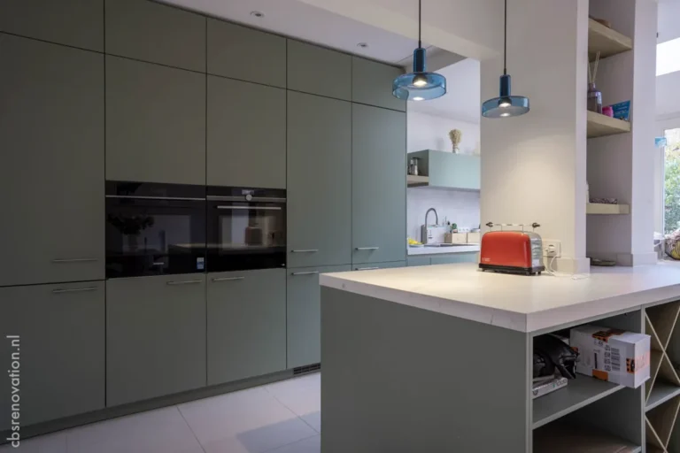 Sage-green kitchen with a central island and built-in appliances