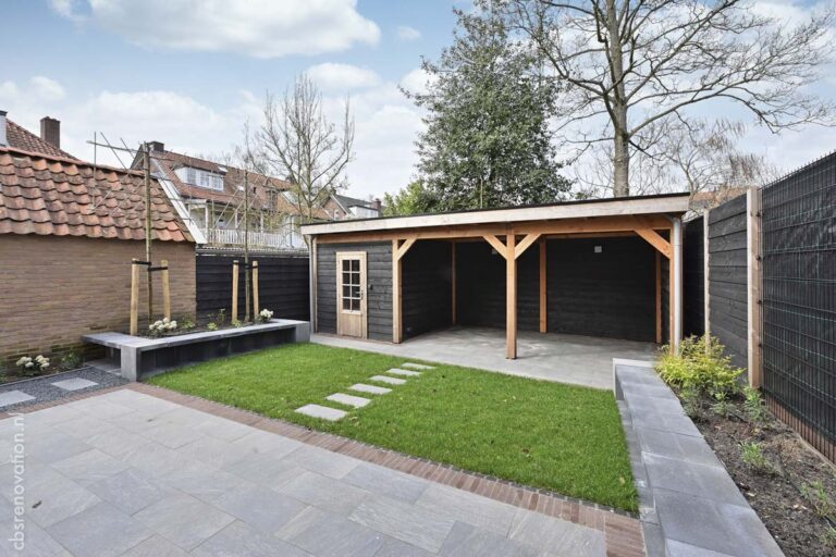 Back garden with a black timber shed on oak posts, lawn and a stone stepping path