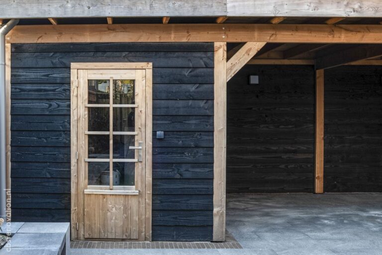 Garden room clad in black timber with oak posts and a glazed door onto the terrace