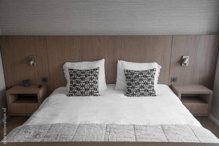 Bedroom with a wood-panelled headboard wall, built-in bedside shelves and reading lights