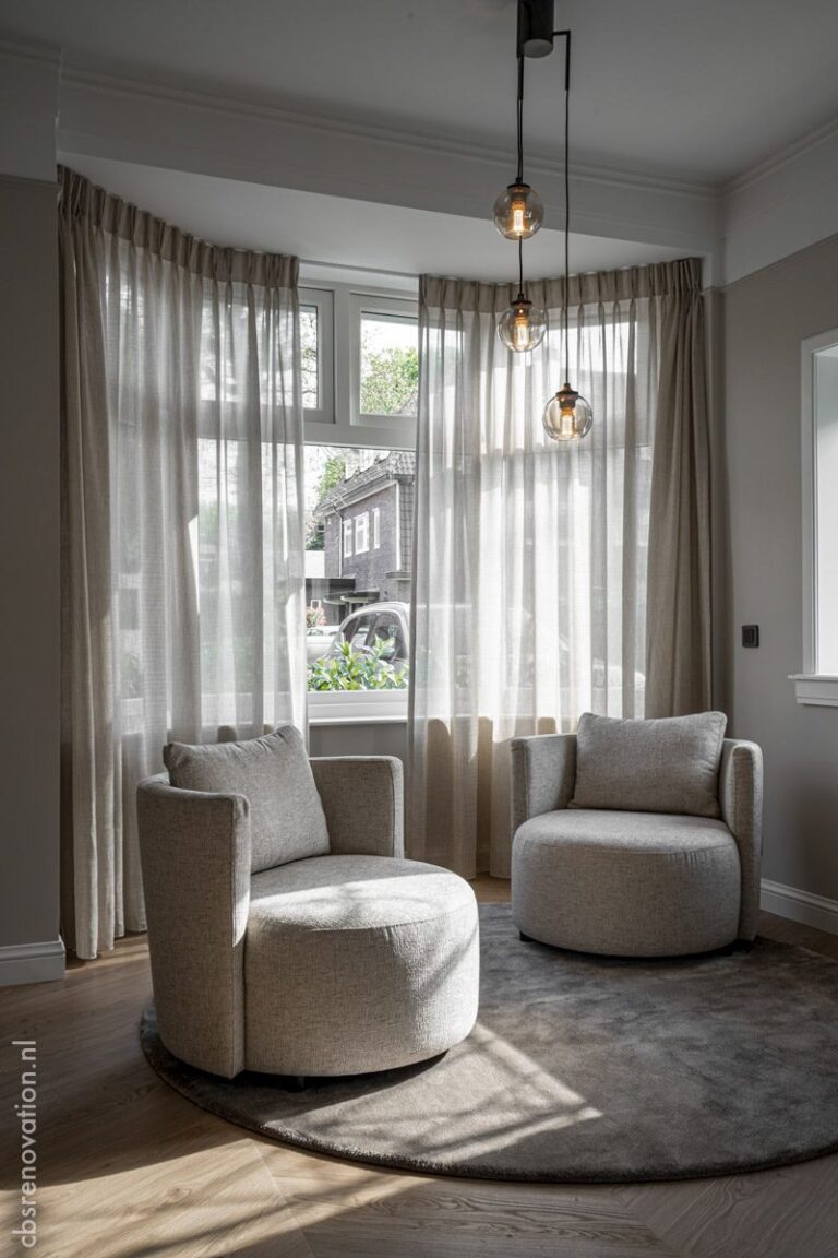Bay window seating area with two swivel chairs and glass pendant lights