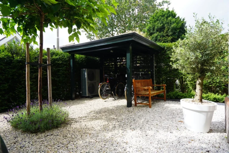 Carport and planted border with an olive tree in the gravel garden